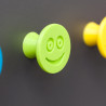 Elastyczna gałka meblowa z uśmiechem, jasnozielona, na ciemnym tle.