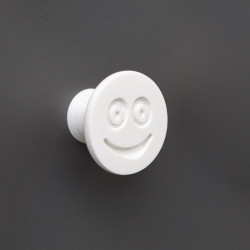 Flexible furniture knob with smile, white, on dark background.