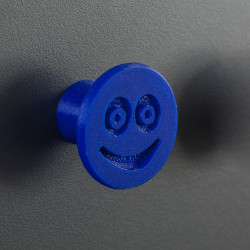 Flexible furniture knob with smile, navy blue, on dark background.