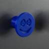 Flexible furniture knob with smile, navy blue, on dark background.